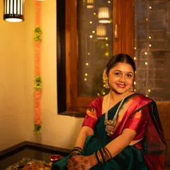 A classic Diwali portrait. The warm indoor lighting, festive decor in the background, and her serene smile create a timeless image that perfectly represents the warmth and joy of the festival.