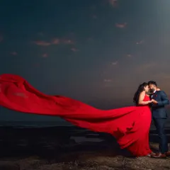Create a dramatic and romantic pre-wedding photo with our signature long-tail gowns. This vibrant red gown provides a stunning contrast against the evening sky.