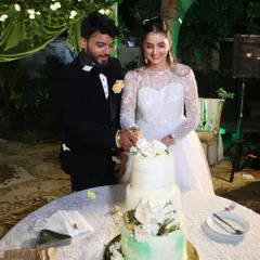 A beautiful moment captured as the happy couple cuts into their three-tiered wedding cake. The design featured a sage green watercolour effect on the bottom tier and was adorned with fresh white flowers.
