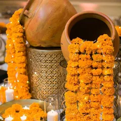 A creative decor idea using old terracotta pots. We created a cascading "waterfall" of marigold flower strings, intertwined with fairy lights and surrounded by candles, to make a stunning and unique entrance decoration.