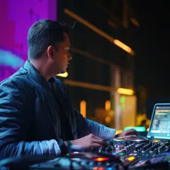 A candid shot of me focused on my laptop, selecting the next track during an outdoor rooftop set.