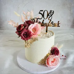 A chic and floral cake for a 50th and fabulous celebration. The combination of burgundy and pink flowers with gold leaf on a textured buttercream cake is simply timeless.