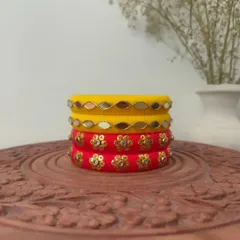 This bright and cheerful set of handmade bangles is perfect for a haldi or mehendi ceremony. It features yellow bangles with mirror work and red bangles with golden floral sequins.