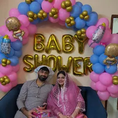 A complete baby shower or godh bharai setup with a pink and blue balloon arch, signifying a celebration for either a boy or a girl.