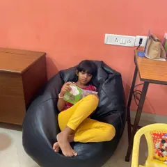 A young reader gets comfortable in a bean bag chair, completely absorbed in her book. We provide various cozy spots for children to settle in and read.