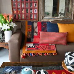 The scrap quilt styled with coordinating cushions, showing how it can be the centerpiece of a warm and eclectic living room.
