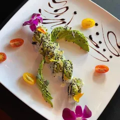 We also offer exquisite sushi platters. This avocado-wrapped dragon roll is beautifully presented with edible flowers and a balsamic glaze, showcasing our attention to detail and artistic plating.