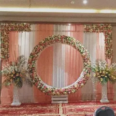 A circular floral ring is a beautiful focal point for any stage. This large ring, covered in pastel roses against a draped backdrop, is perfect for engagements or receptions.