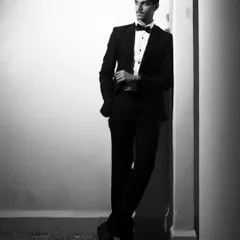A classic black and white portrait of a male model in a tuxedo. The hard light creates sharp lines and a timeless, formal look perfect for a portfolio.