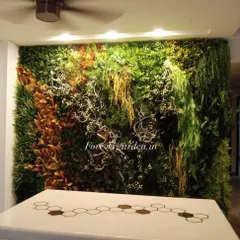 This is a highly artistic and textured green wall we designed for a residence. It combines different types of foliage, including hanging ferns and colorful accents, to create a living piece of art above a console table.