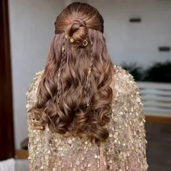 A closer look at this intricate half-up hairstyle. The bun, braids, and delicate gold charms create a look that is both bohemian and incredibly chic for a cocktail night.