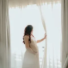 A quiet, dreamy moment before the baby shower. This beautiful shot captures the anticipation and joy, with the client wearing one of our elegant gowns.