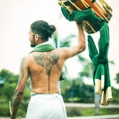 Strength and artistry combined. A shot from behind, showing the powerful physique required to master the chenda.