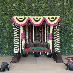 A traditional floral jhoola, or swing, is a beautiful centerpiece for ceremonies like a baby shower or Mehendi. This one is meticulously decorated with fragrant white and pink flowers against a living green wall, blending tradition with a fresh, modern aesthetic. It provides a perfect spot for photos and blessings.