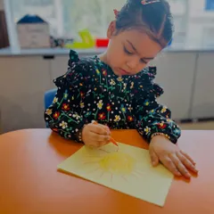 A duplicate of ID 17, this image shows a young girl completely absorbed in her drawing, a quiet but powerful moment of creative expression.