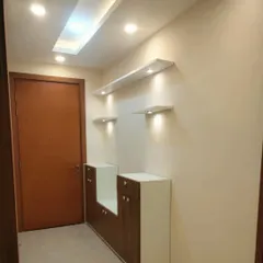 The entryway of a newly painted apartment. The soft, neutral wall colour complements the warm wood of the door and the modern lighting fixtures, creating a welcoming first impression.