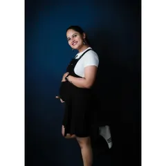A full-length version of a playful solo studio portrait. The casual outfit and happy pose create a modern and fun image that showcases the mom-to-be's personality.