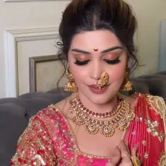 A close-up of a classic Maharashtrian bridal makeup look, focusing on the traditional bindi, nath, and warm, golden eye makeup.