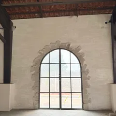 A unique detail from one of our projects. We created a faux stone archway around this large window, adding architectural character to a plain wall using only texture and paint.