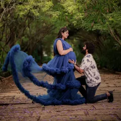 Capture a tender moment with your partner during your maternity shoot. This royal blue ruffled gown not only looks stunning but is also designed for comfort, allowing for beautiful poses like this one.