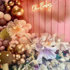 The "Oh Baby" neon sign glows against the pink shiplap backdrop, surrounded by delicate organza flowers and a cascade of balloons. This shows how I use lighting and texture to create a dreamy effect.