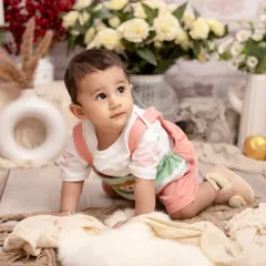 On the move. This shot captures a baby during their crawling phase, exploring a beautiful floral set. It's a perfect way to remember their first big steps toward independence.