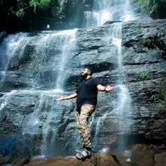 A trekker standing in awe of a powerful waterfall.
