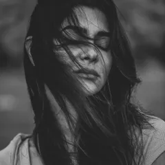 The wind blowing through the model's hair creates a powerful sense of movement and emotion in this black and white portrait. With eyes closed, the image feels introspective and raw, focusing on the feeling rather than a direct gaze.