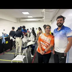 A coach poses with a student during a busy competition day. We foster a supportive environment where coaches and athletes celebrate progress together.