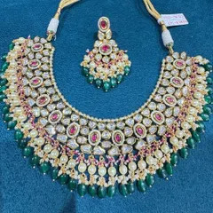 A beautiful bib-style necklace featuring fine kundan work, pearls, and a mix of ruby and emerald colored stones.