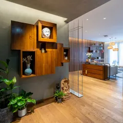 This custom foyer unit is a composition of interlocking wooden boxes, creating a play of solid volumes and open voids for displaying art and artifacts. It serves as a functional and sculptural focal point at the entrance of the home.
