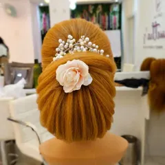A classic French bun with a modern twist, accessorized with a delicate flower and pearl hairpiece. This is a versatile look for receptions or parties.