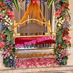 A close-up of the beautifully decorated swing for a Teej function, adorned with a variety of fresh flowers and a floor scattered with rose petals.