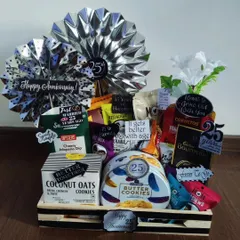 This stylish silver jubilee hamper marks a 25th anniversary with elegance. The black and silver theme is carried through with metallic fans, and the basket is filled with premium cookies, nuts, and other gourmet snacks.