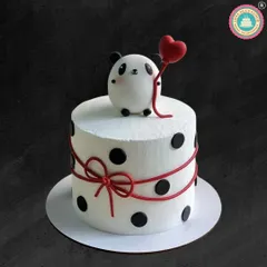 Cuteness overload with this minimalist panda cake. A sweet little panda holds a red heart balloon, sitting atop a white cake with black polka dots and a delicate red ribbon.