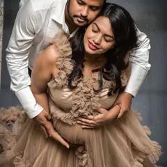An intimate studio maternity portrait. This mom-to-be wears a beautiful beige ruffled gown that adds texture and elegance to this tender moment.