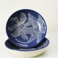 This set of Dutch Iris pasta bowls features a detailed floral design I carve by hand before glazing. The deep blue interior contrasts beautifully with the off-white exterior.