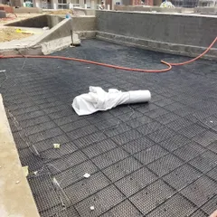 Here you can see the drainage cell system being laid out over a large area. This lightweight and strong material creates a void for water to drain, which is essential for rooftop and podium gardens.