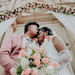 A low-angle shot capturing an intimate moment between the bride and groom under a floral arch at the church entrance, with their garlands adding a touch of fusion tradition.
