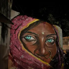 A powerful mural of a woman with striking blue eyes, her face partially covered by a sari, found on a wall in Pushkar.