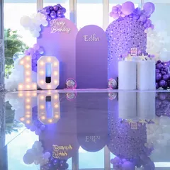 A dream in lavender for a 10th birthday party. This picture perfect setup, inspired by the movie 'Wish', features a custom backdrop with balloon art and marquee lights, all reflected for a touch of magic.