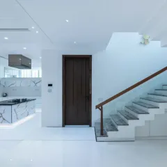 This view highlights the seamless integration of the kitchen into the open-plan living space. The all-white cabinetry and island with a striking stone pattern blend perfectly with the home's minimalist aesthetic.