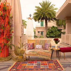 A Mehendi setup that speaks the language of joy. This cozy corner at ITC Grand Bharat combines a colorful patchwork rug, printed cushions, and a pop of red from bamboo sticks and florals.