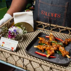 It's all in the details. A server presents Thai Style Chicken Satay on a rustic woven tray, complete with a business card and a small floral arrangement.