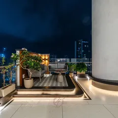 A cozy lounge area on the terrace, perfect for enjoying the stunning city skyline at night. The elevated platform and patterned rug define the space, while the surrounding planters add a touch of nature.
