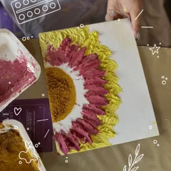 A close-up of a textured sunflower painting in progress. You can see the thick, sculpted petals created with a palette knife, adding a beautiful 3D effect to the artwork.