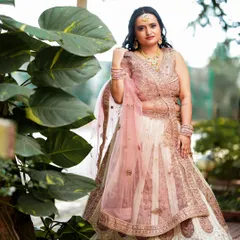An elegant bridal portrait in a garden setting, showcasing a beautiful pink and white lehenga.