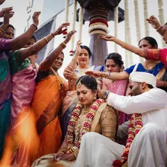 A vibrant, candid moment as family members shower the couple with blessings during a South Indian wedding ritual. This image is full of color, emotion, and the joy of community.