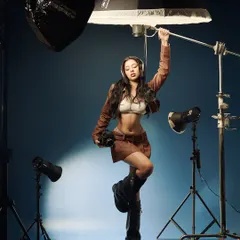 A self-aware moment on set. This shot playfully breaks the fourth wall, showing the model interacting with the tools of the trade. It’s a reminder that even in high-fashion, we can have fun with the process.