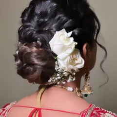 A modern take on the floral bun. This textured, low bun is decorated with fresh white roses, creating a look that is both romantic and sophisticated.
